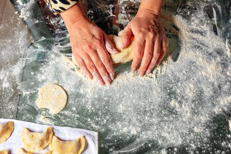 A woman kneads the dough with her hands and prepares tasty and satisfying dumplings. Ukrainian national cuisine, close-up, copy space.の写真素材