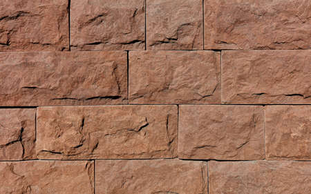 Wall background and texture of brown granite tiles with chips around the perimeter, close-up.