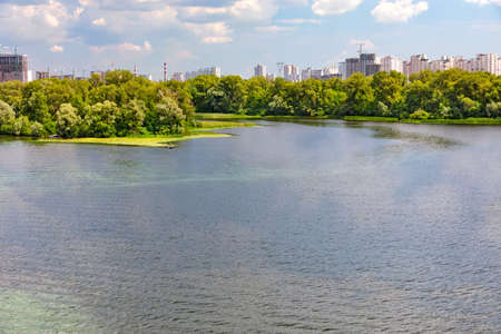 The beautiful bay of the Dnipro with the banks overgrown with reeds, a fishing boat moored to the shore, and on the horizon is the city's residential area under construction is visible of Kyiv.の写真素材