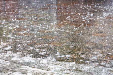 Large raindrops form an abstract pattern on the surface of the granite square of the city sidewalk. Selective focus, soft gradient of light and shadow.の写真素材
