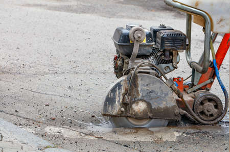 A mobile petrol cutter in the process of work and precisely cuts the asphalt with a diamond cutting...