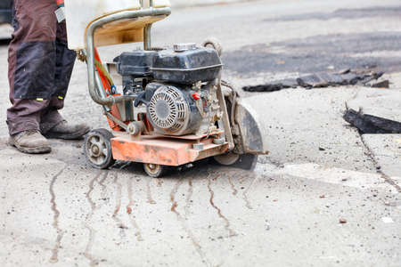 The petrol cutter smoothly cuts the asphalt with a diamond cut-off wheel along the marked line....