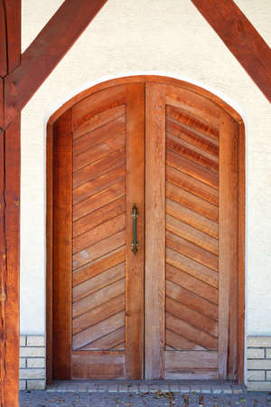 Entrance wooden doors of an old Ukrainian village hut with a massive brass handle and slanting even planks.の写真素材