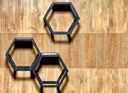 Metal black cubic stylish shelves with hex cutouts on a wooden wall background, copy space.の写真素材