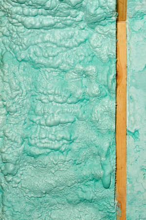 Texture and background of a wall made of ecological light green construction foam, laid in parallel rows near a wooden beam. Vertical image, close-up, high resolution.の写真素材