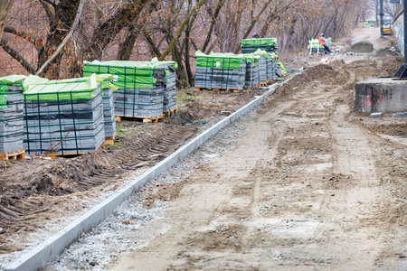 Paving slabs in stacks are located along the construction site of the city park walking path. Laying paving slabs on the footpath. Copy space, selective focus.の写真素材