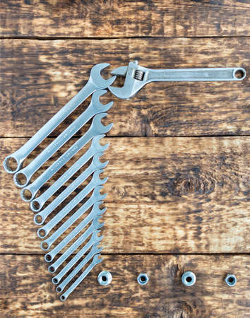 A set of wrenches with chrome vanadium and an adjustable wrench on a background of old wooden boards. Copy space, vertical image, close-up.の写真素材