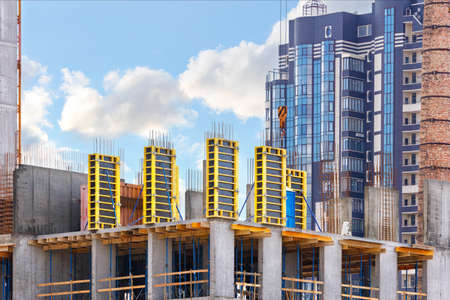 A fragment of the construction of a new building using a monolithic-frame method with a formwork system for the supporting structures of the house against a clear sky background. Copy space.の写真素材