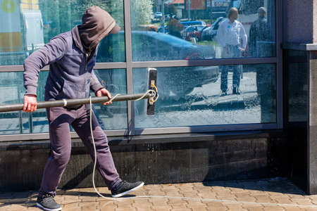 A window cleaner washes the glass facade of a building with a mop and an automatic soapy water...