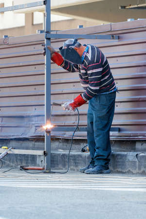 A bright welding arc at the welder's workplace in a protective helmet and gloves, who welds the...