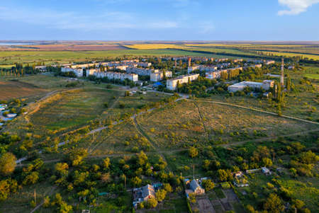 Aerial photography, evening sunset light falls on the working village and the fields around in...