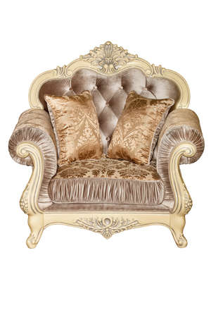 Beautiful soft armchair upholstered in expensive brocade textile upholstery in brown and beige, with soft pillows, with curved ivory carved legs, photographed from the front, isolated on a white background.の写真素材