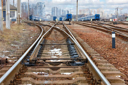 Railway automatic arrow closeup against the background of a network of branched railway tracks with trains standing on them.の写真素材