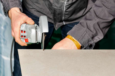 Worker cut tiles. Cutting ceramic tiles with a manual electric grinder with a diamond blade. copyspace. closeup.の写真素材