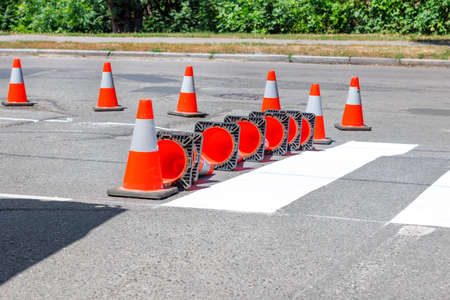 A road worker using a paint sprayer applies white road markings to a crosswalk using a wooden template. copyspace.の写真素材