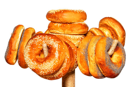 Appetizing bagels are topped with sesame seeds and poppy seeds hanging on a rack. Isolated on white Background. Selective focus.の写真素材