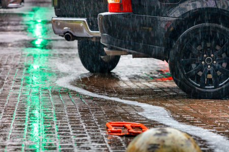Heavy rain in the parking lot and the reflection of the green light of a traffic light on a city...