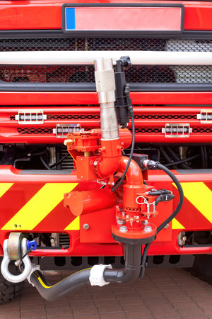 Detailed view of vibrant fire truck front with red hoses, valves, key equipment for rescue operations conceptの写真素材