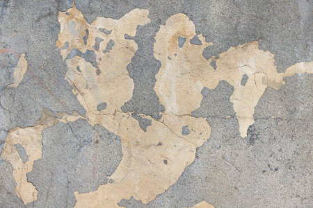A weathered concrete surface showcases a faded world map formed by cracks and peeling paint. The earthy tones and irregular shapes create a unique artistic effect, evoking exploration and nostalgia.の写真素材