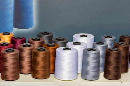 Spools of colorful thread in various shades create a lively display in a sewing studio. The setup...