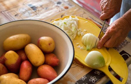 Cooking vegetables at home. In the foreground is a bowl of potatoes. Next, cut the onion on the...