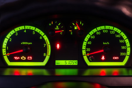 The green glow of the car's dashboard at night. Speedometer and car tachometer close-up.の写真素材