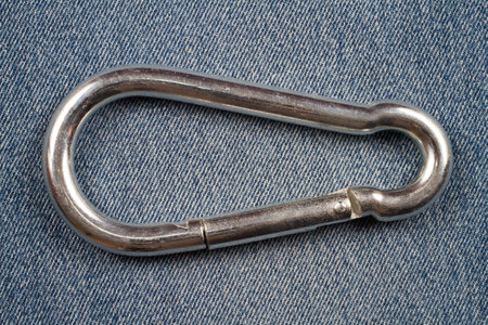 Firefighter carbine on denim background. Metal carabiner close-up.