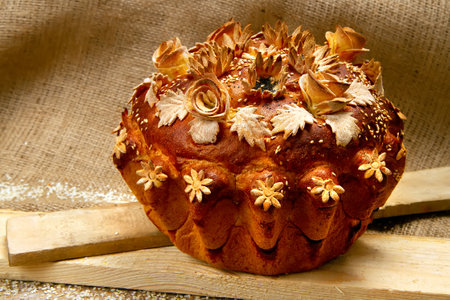 A loaf of bread decorated with flowers and patterns. Wedding loaf on the background of burlap.の写真素材