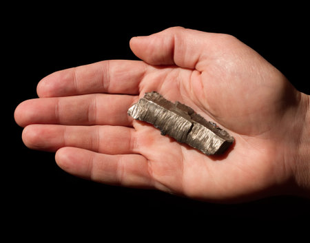 A fragment of a bomb in the palm of a man. Palm with a fragment of a bomb on a black background.の写真素材
