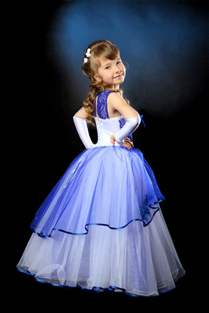 A girl in a ball gown on a dark background is turned back.の写真素材