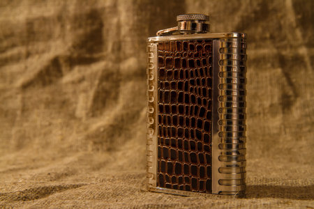 Metal flask for alcohol on the background of burlap.の写真素材