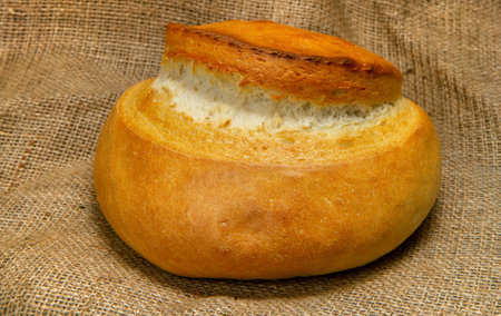 A loaf of bread against the background of burlap. A round loaf of bread with a crispy crust.の写真素材