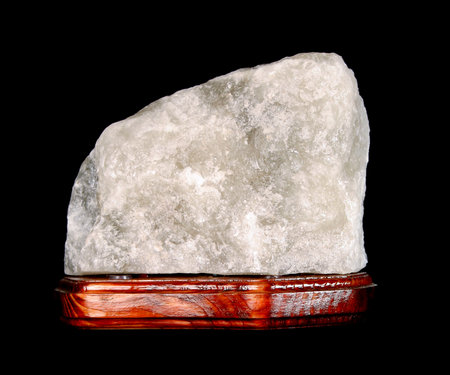 Salt lamp on a black background. Close-up salt lamp. A block of salt on a wooden stand.の写真素材