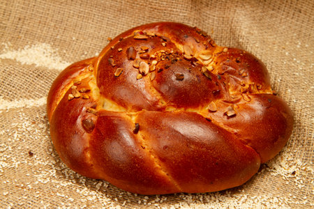 Buttery sweet bun. Bakery product on the background of burlap. Bun with sesame and nuts close-up.
