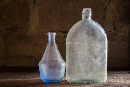 Dusty vintage bottles. Antique glassware on an old shelf. Two glass bottles.の写真素材