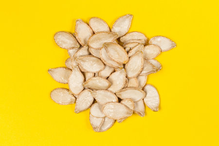 A bunch of pumpkin seeds on a yellow background. Dry pumpkin seeds.の写真素材