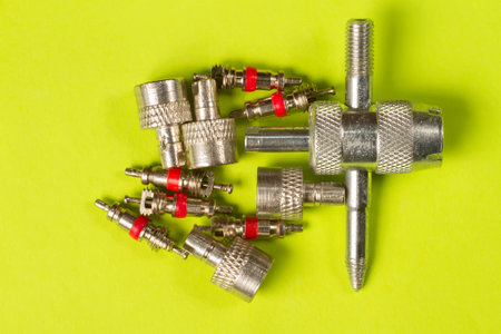Caps, valves and a special wrench for repairing car wheels. Spare parts for a car on a green background.の写真素材