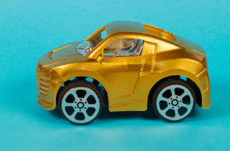 A toy car of gold color on a blue background. The machine has a yellow grainy color.の写真素材