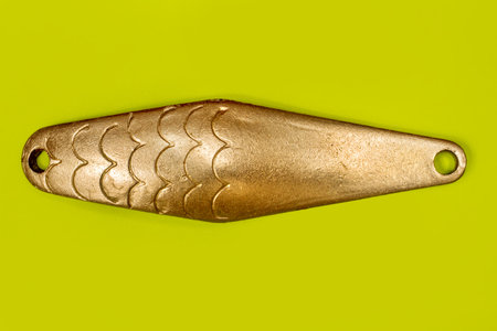 Fishing gear and accessories. Metal fishing spinner close-up on a green background.の写真素材