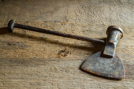 An old iron hatchet against a background of rough boards. Rusty old hatchet.