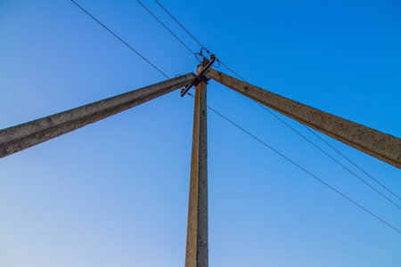 Triple pole of power lines against the sky. Triple concrete support with electrical wires.の写真素材