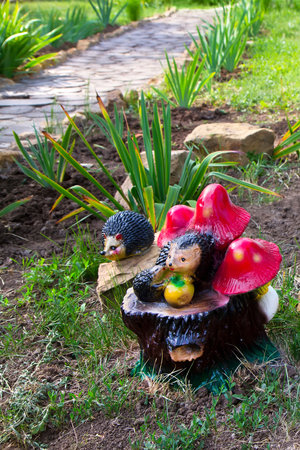 Garden ceramic figurines of hedgehogs. Toy mushrooms and hedgehogs on a stump. Landscaping of the garden.の写真素材