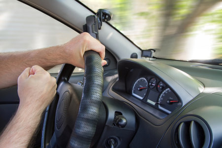 An aggressive driver driving a car exceeds the speed limit. Dangerous aggressive driving. The interior of the car. Men's hands.の写真素材