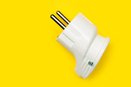 Electric plug on a yellow background. White plastic electrical plug.