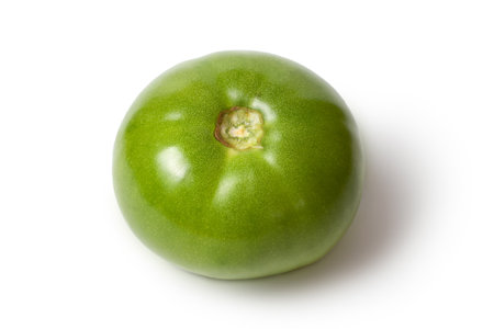 Green tomato on white background. Green tomato with shade. Unripe tomato close-up.の写真素材