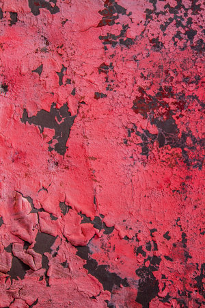 Vertical texture of pink flaky paint on a black surface. Abstract background texture.