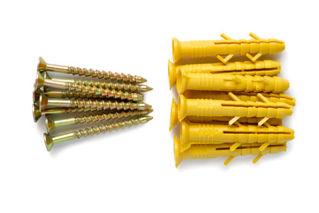 Yellow plastic dowels and metal screws on a white background. Modern fasteners.