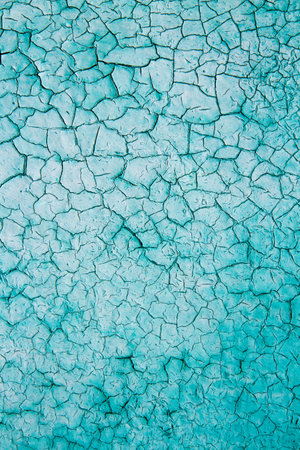 Vertical texture of old blue cracked paint. The surface of the weathered paint is cracked.