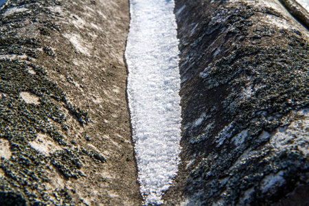 Melting spring snow on an old slate roof. Snow on the roof under the rays of the sun.の写真素材