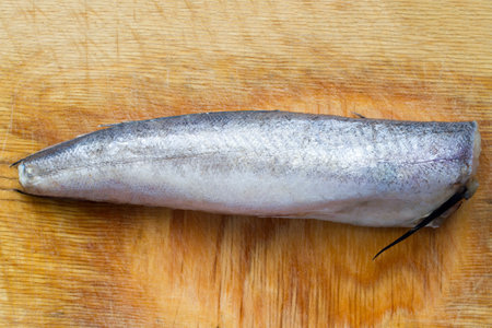 Fresh sea fish on a wooden cutting board. Frozen fish without a head.